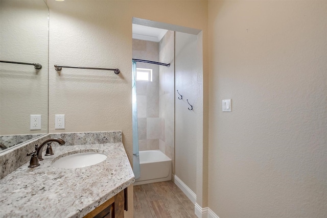 bathroom with tiled shower / bath combo, vanity, and hardwood / wood-style flooring