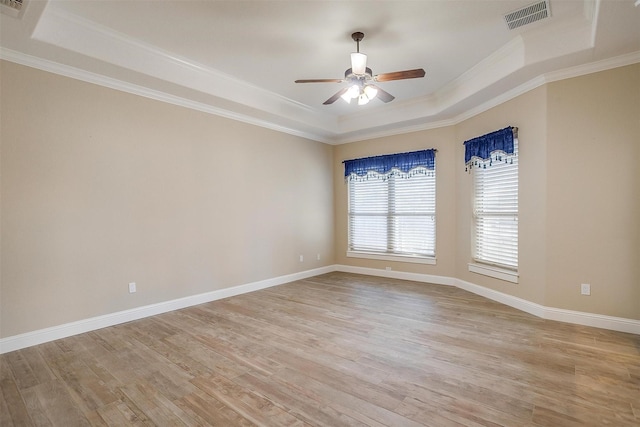 spare room featuring ornamental molding, light hardwood / wood-style flooring, ceiling fan, and a tray ceiling