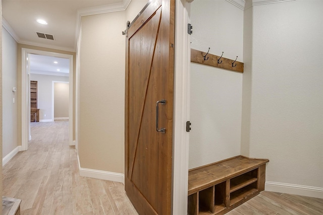 mudroom with ornamental molding, a barn door, and light wood-type flooring