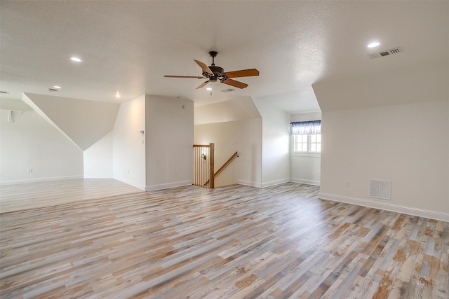 additional living space with ceiling fan, lofted ceiling, and light wood-type flooring