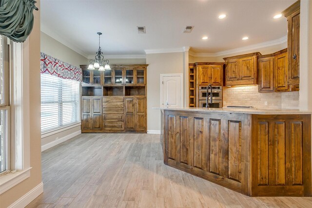 kitchen featuring decorative backsplash, crown molding, stainless steel double oven, and light wood-type flooring