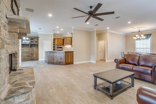 living room with a fireplace, ornamental molding, ceiling fan with notable chandelier, and light wood-type flooring