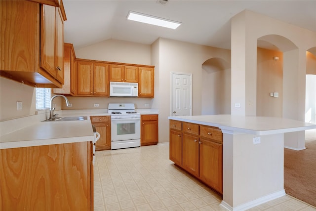 kitchen featuring lofted ceiling, sink, white appliances, and a center island