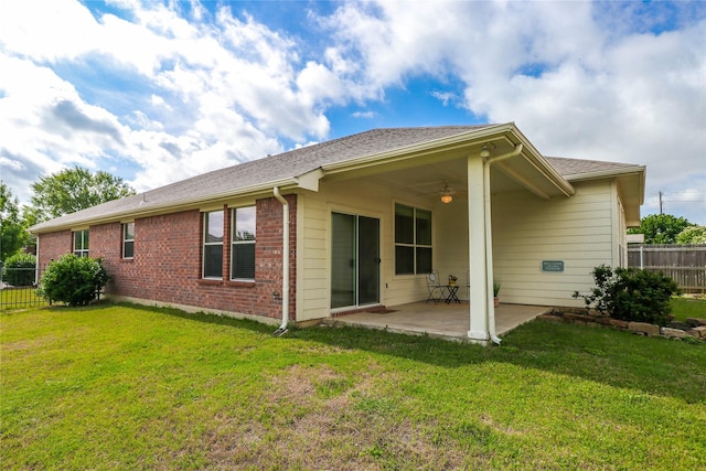 rear view of property featuring ceiling fan, a patio, and a lawn