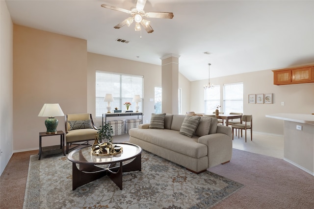 carpeted living room with ceiling fan with notable chandelier, plenty of natural light, ornate columns, and vaulted ceiling