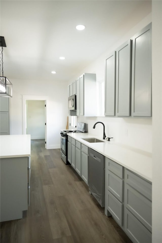 kitchen with dark hardwood / wood-style floors, sink, gray cabinetry, hanging light fixtures, and stainless steel appliances