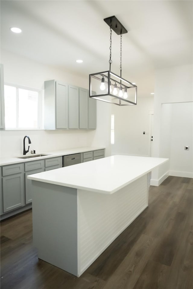 kitchen featuring gray cabinets, sink, dark hardwood / wood-style flooring, hanging light fixtures, and a center island