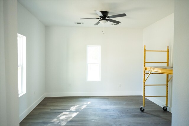 unfurnished room featuring ceiling fan, dark hardwood / wood-style floors, and a healthy amount of sunlight