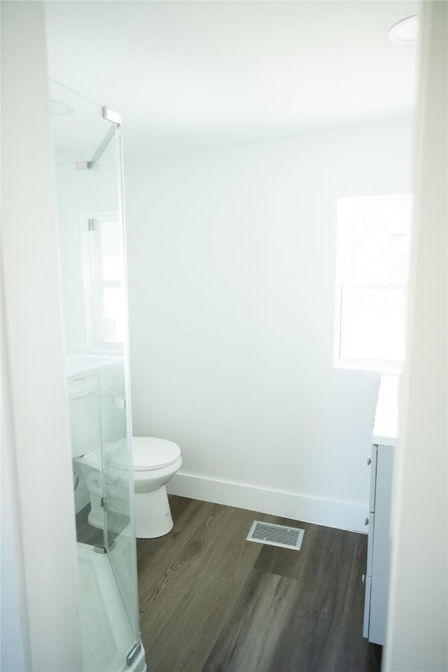 bathroom with hardwood / wood-style flooring, vanity, toilet, and walk in shower