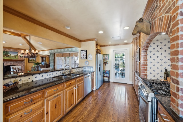 kitchen featuring sink, dark wood-type flooring, dark stone countertops, decorative backsplash, and appliances with stainless steel finishes