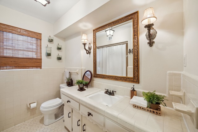 bathroom with tile patterned flooring, vanity, toilet, and tile walls