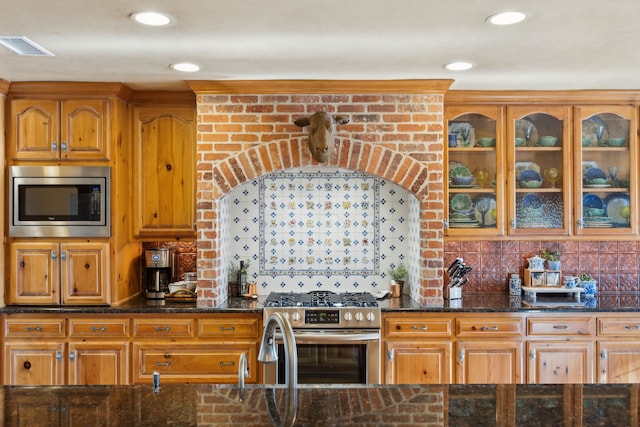 kitchen featuring dark stone countertops, decorative backsplash, and stainless steel appliances