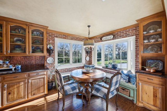 dining room with dark hardwood / wood-style floors, a wealth of natural light, brick wall, and a chandelier