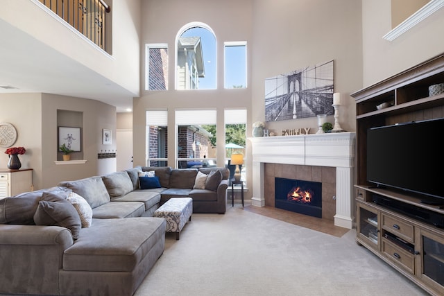 carpeted living room featuring a tile fireplace and a towering ceiling