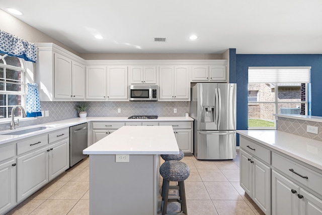 kitchen featuring sink, a center island, light tile patterned floors, and appliances with stainless steel finishes