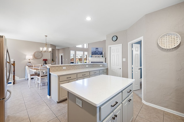 kitchen featuring light tile patterned flooring, a notable chandelier, stainless steel fridge, decorative light fixtures, and a kitchen island