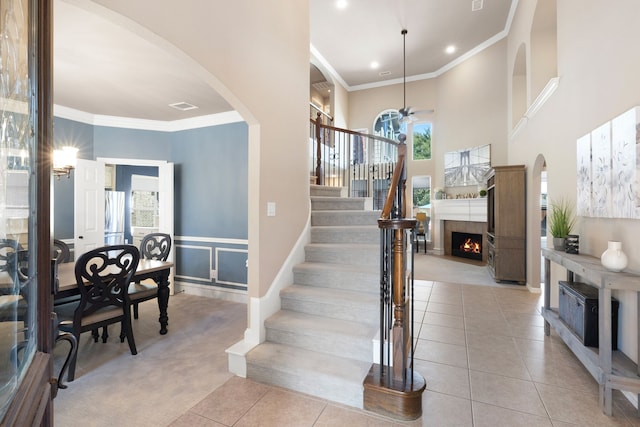 staircase with a wealth of natural light, tile patterned flooring, and ornamental molding