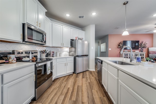 kitchen featuring white cabinetry, sink, hanging light fixtures, decorative backsplash, and appliances with stainless steel finishes