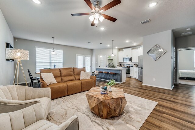 living room featuring ceiling fan and dark hardwood / wood-style floors