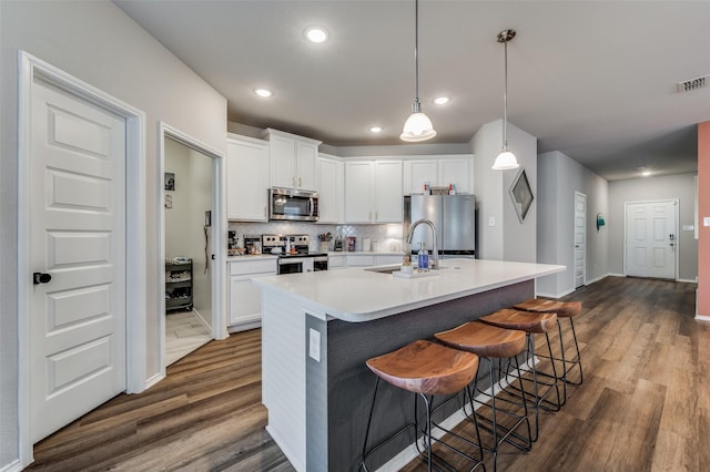 kitchen featuring white cabinets, appliances with stainless steel finishes, decorative backsplash, and hanging light fixtures