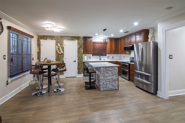 kitchen featuring sink, appliances with stainless steel finishes, hanging light fixtures, ventilation hood, and a kitchen island