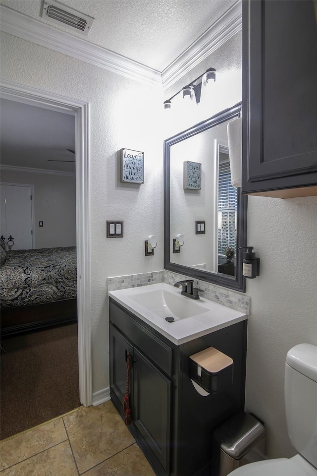 bathroom featuring tile patterned flooring, vanity, toilet, crown molding, and a textured ceiling