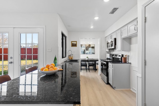 kitchen with dark stone counters, stainless steel appliances, sink, light hardwood / wood-style floors, and white cabinetry