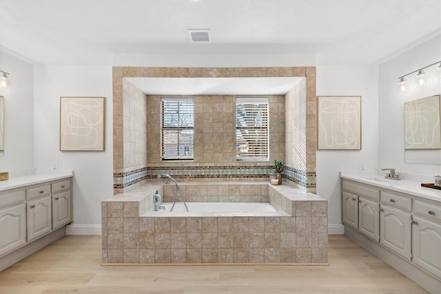 bathroom featuring hardwood / wood-style flooring, vanity, and tiled tub