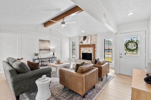 living room with vaulted ceiling with beams, ceiling fan, light hardwood / wood-style floors, and a fireplace