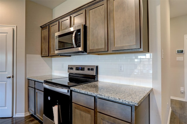 kitchen featuring decorative backsplash, light stone counters, dark hardwood / wood-style flooring, and appliances with stainless steel finishes