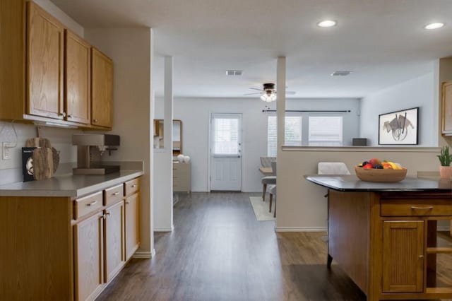 kitchen featuring a breakfast bar area, ceiling fan, and dark wood-type flooring