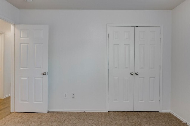 unfurnished bedroom with light carpet and a closet