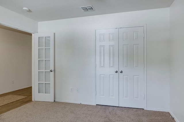 unfurnished bedroom with light carpet and a closet