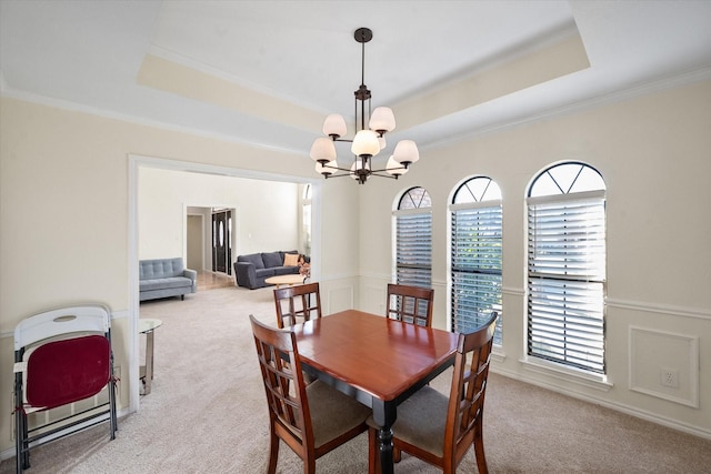 carpeted dining area with a chandelier, a raised ceiling, and crown molding