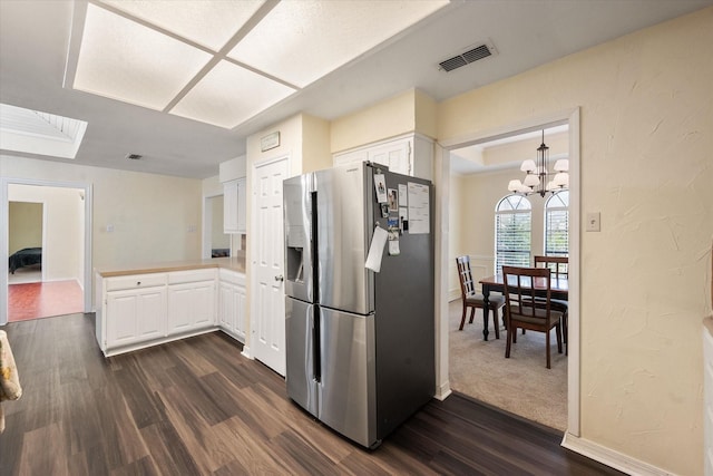 kitchen featuring dark wood-type flooring, white cabinetry, a chandelier, stainless steel fridge, and kitchen peninsula