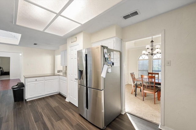 kitchen featuring pendant lighting, white cabinets, dark hardwood / wood-style floors, stainless steel fridge, and a chandelier