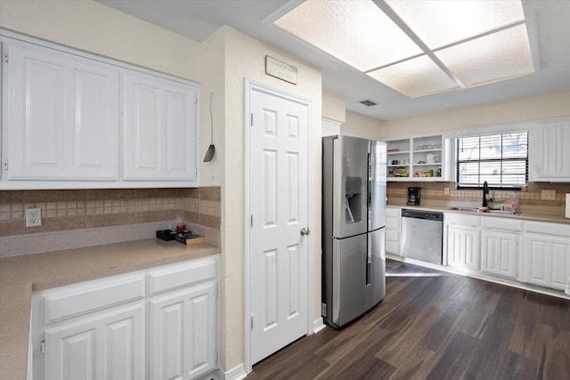 kitchen with sink, dark wood-type flooring, stainless steel appliances, backsplash, and white cabinets