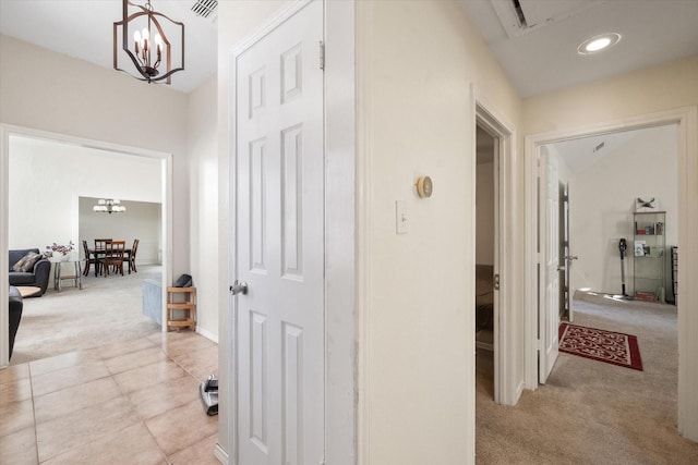 corridor with light colored carpet and a chandelier