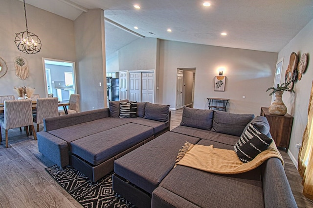 living room featuring high vaulted ceiling, wood-type flooring, and an inviting chandelier