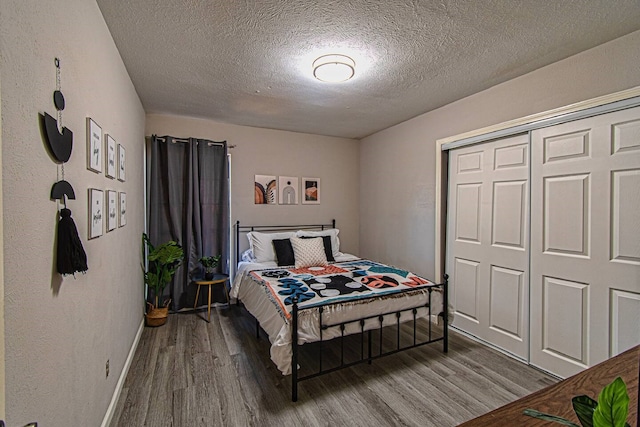 bedroom with a closet, wood-type flooring, and a textured ceiling