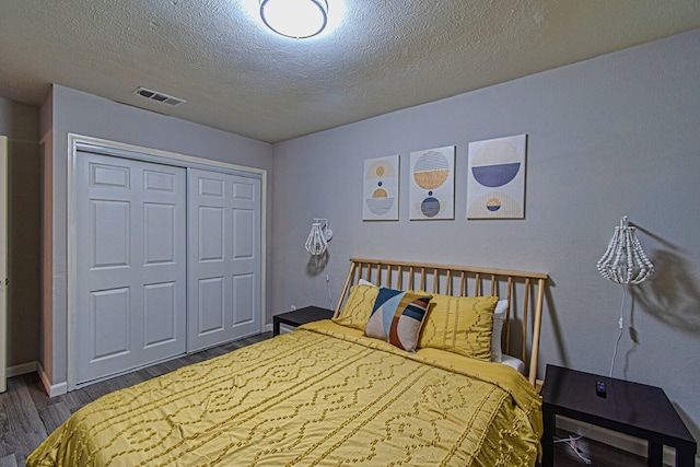 bedroom with dark hardwood / wood-style floors, a textured ceiling, and a closet