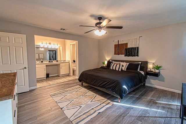 bedroom with ensuite bathroom, light hardwood / wood-style flooring, and ceiling fan