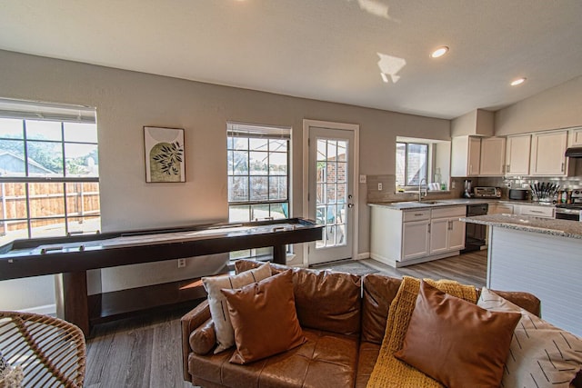 kitchen featuring light stone countertops, tasteful backsplash, vaulted ceiling, wood-type flooring, and white cabinets