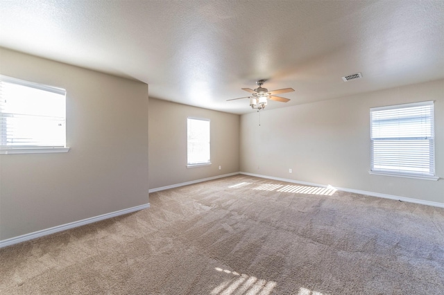 carpeted empty room with a wealth of natural light and ceiling fan