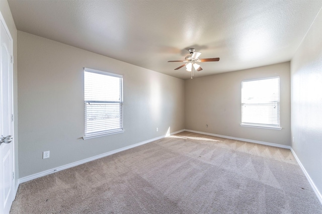 spare room with a textured ceiling, ceiling fan, and light carpet