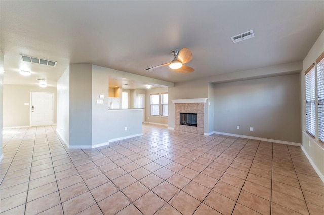 unfurnished living room with ceiling fan, a fireplace, and light tile patterned flooring