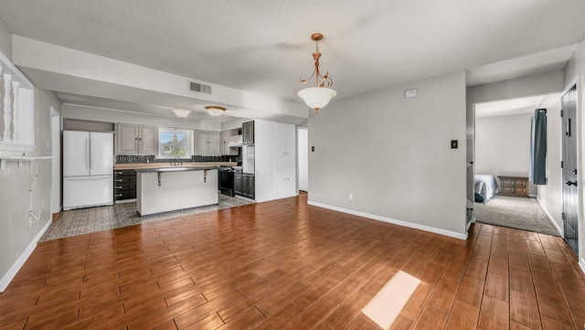 kitchen with sink, a breakfast bar, a kitchen island, decorative light fixtures, and white fridge