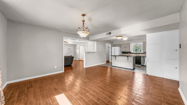 unfurnished living room with dark hardwood / wood-style flooring, sink, and a textured ceiling