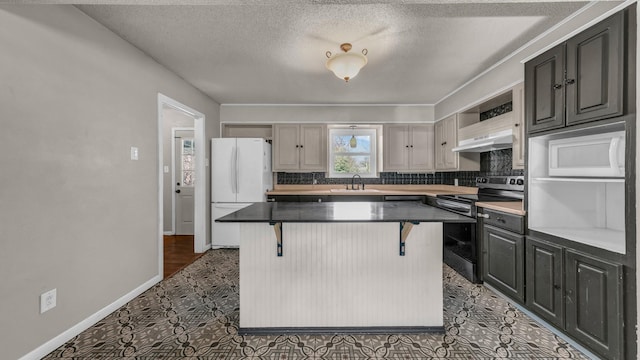 kitchen featuring sink, stainless steel electric range, a breakfast bar area, and a center island