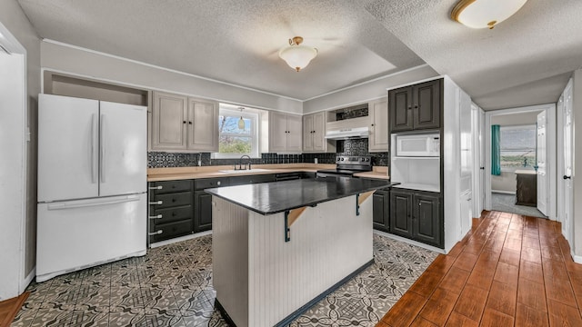 kitchen with a kitchen island, gray cabinetry, a kitchen breakfast bar, decorative backsplash, and white appliances